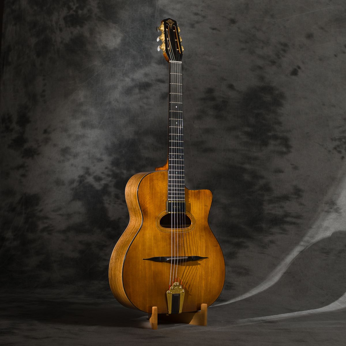 La guitare manouche vue de face : pan coupé, petite bouche ovale, micro au bout de la touche